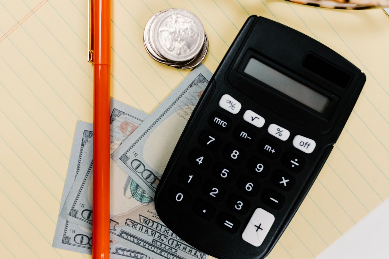 services-04 Close-up image of a calculator, pen, and currency on a yellow notepad, symbolizing finance.