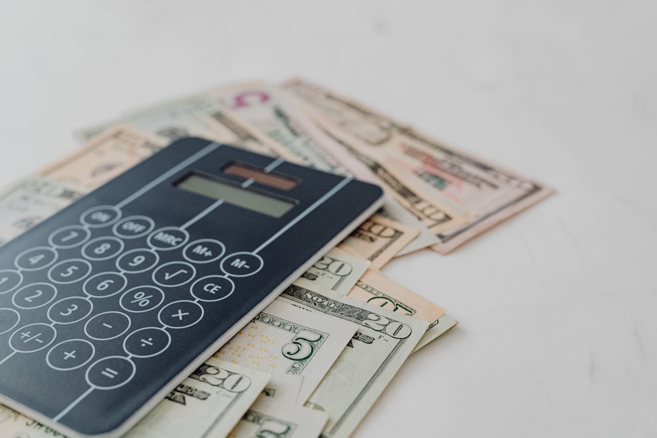 services-01 A close-up of a calculator and US dollar banknotes, symbolizing financial calculation and budgeting.